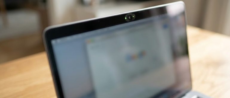 Ноутбук со встроенной веб-камерой и включённым индикатором на рабочем столе